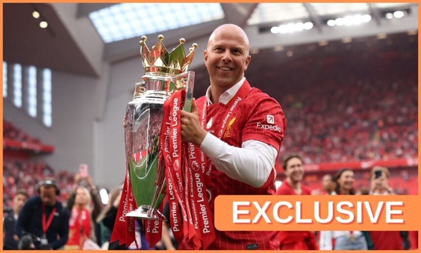 Arne Slot holds the Premier League trophy on the pitch at Anfield.