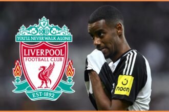 Alexander Isak rubs his face with his shirt next to Liverpool club crest.