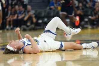#2 Brandin Podzemski of the Golden State Warriors lies on the floor in pain after colliding with #24 Kobe Brown of the LA Clippers during the first half of an NBA preseason basketball game at Chase Center.