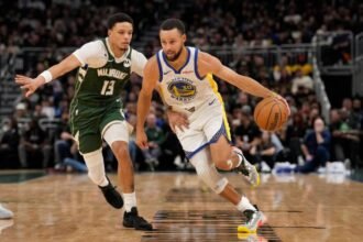 Golden State Warriors' No. 30 Stephen Curry dribbles the ball against Milwaukee Bucks' No. 13 Ryan Rollins during the second quarter at Fiserv Forum.