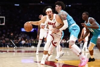 Jaime Jaquez Jr. #11 of the Miami Heat dribbles the ball into the basket against LaMelo Ball #1 of the Charlotte Hornets during the first quarter of a game at Caseya Center on October 28, 2025 in Miami, Florida.