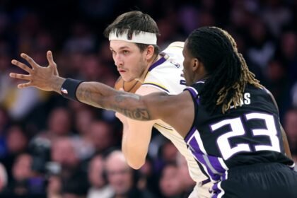 Austin Reaves #15 of the Los Angeles Lakers controls the ball and #23 Keon Ellis of the Sacramento Kings defends during the second half of a game at Crypto.com Arena on December 28, 2024.