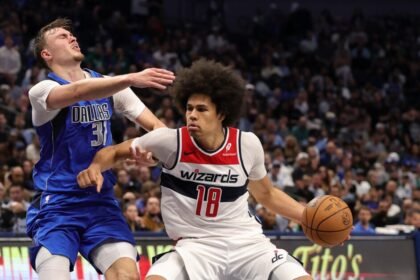 Cooper Flagg #32 of the Dallas Mavericks is fouled by Kyshawn George #18 of the Washington Wizards.