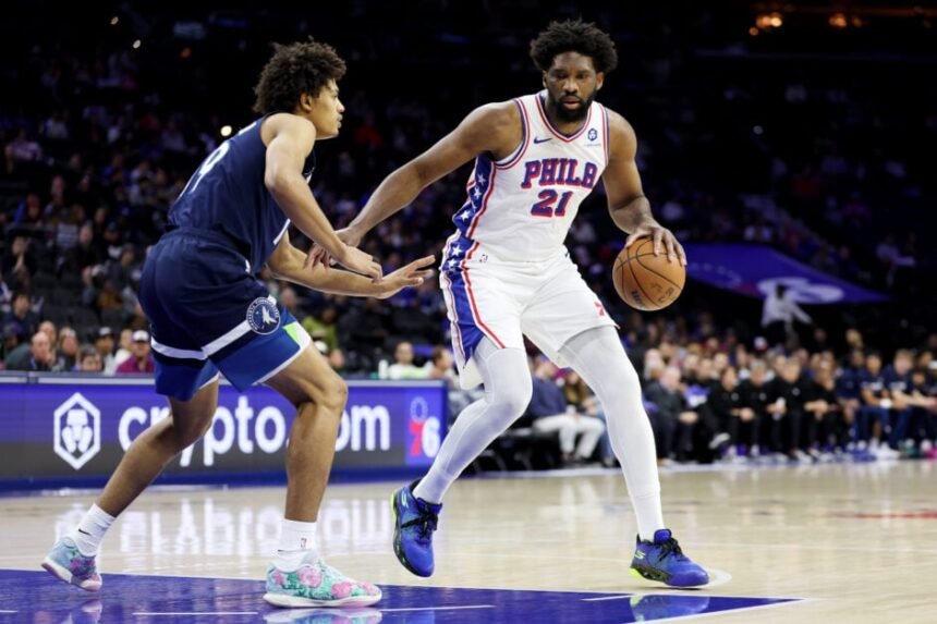 Joel Embiid #21 of the Philadelphia 76ers drives with #19 Joan Bellinger of the Minnesota Timberwolves during the first half at Xfinity Mobile Arena on October 17, 2025 in Philadelphia, Pennsylvania.