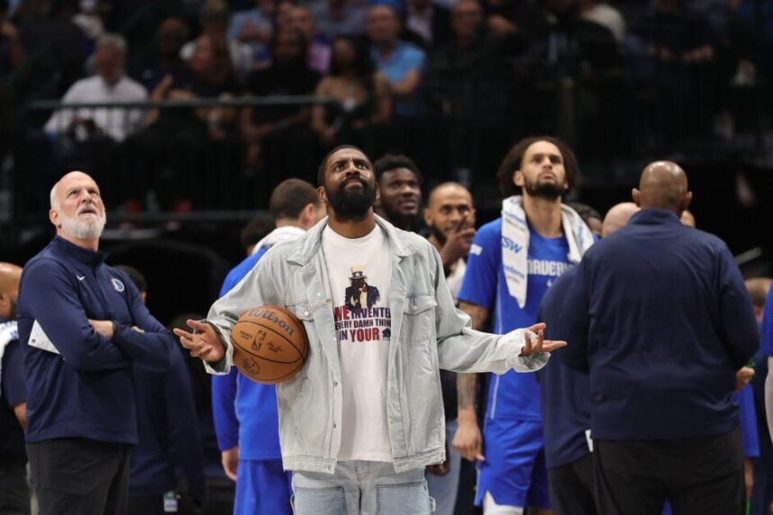 The Dallas Mavericks bench centered around Kyrie Irving. Staring at the scoreboard to watch the replay of the play.