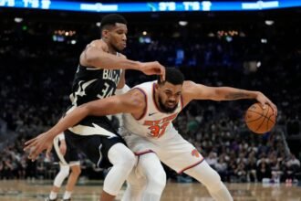 Karl-Anthony Towns #32 of the New York Knicks dribbles the ball against #34 Giannis Antetokounmpo of the Milwaukee Bucks during the third quarter at Fiserv Forum.
