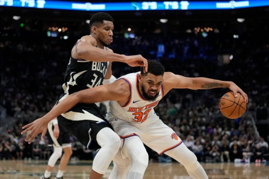 Karl-Anthony Towns #32 of the New York Knicks dribbles the ball against #34 Giannis Antetokounmpo of the Milwaukee Bucks during the third quarter at Fiserv Forum.