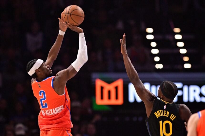 Shai Gilgeous-Alexander #2 of the Oklahoma City Thunder attempts a shot in front of Jimmy Butler III #10 of the Golden State Warriors.